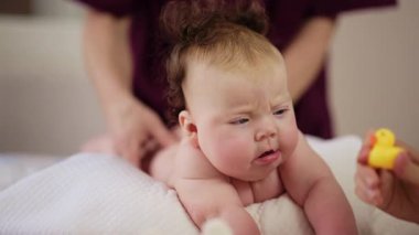 Baby lying on their tummy while an adult massages them and performs mobility exercises