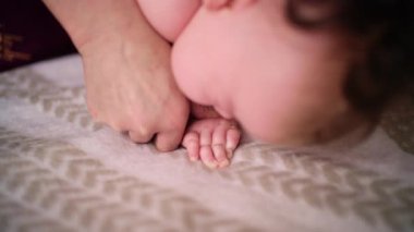 Bebek karnının üstünde yatarken bir yetişkin onlara masaj yapıyor ve hareket egzersizleri yapıyor.