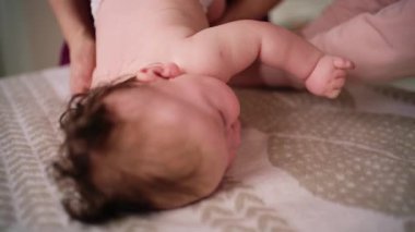 Bebek karnının üstünde yatarken bir yetişkin onlara masaj yapıyor ve hareket egzersizleri yapıyor.