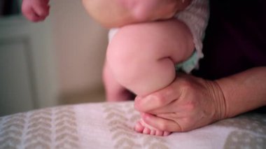 Bakıcı bebekle hareket egzersizi yapıyor.