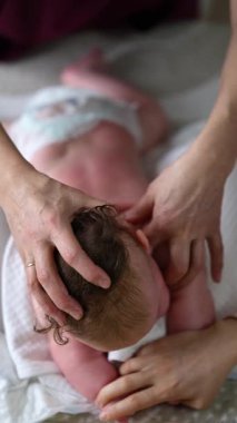 Bebek sırt üstü yatarken bir yetişkin onlara masaj yapıyor ve hareket egzersizleri yapıyor.