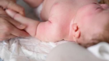 Yetişkinlerin ellerine yaklaş. Bebeğin koluna ve avucuna nazikçe masaj yap.