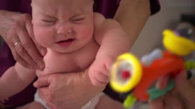 Bebek, bir bakıcının koluna yüz üstü uzanıyor, güvenli bir şekilde destekleniyor.
