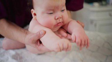 Infant raising head while supported on tummy, strengthening neck muscles during early development