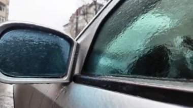 Buz ve erimiş suyla kaplı bir arabanın yan aynasını kapat.