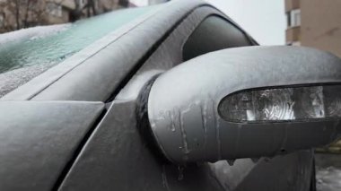 Buz ve erimiş suyla kaplı bir arabanın yan aynasını kapat.