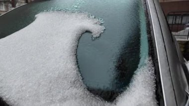 Arabanın ön camında kısmen erimiş buz, şeffaf olmayan bir yama oluşturuyor.