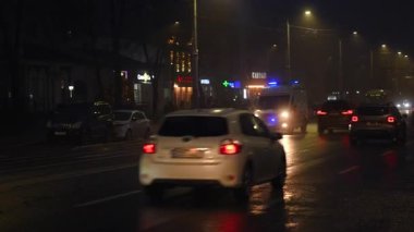 Chisinau, Moldova - 28 Ocak 2026: Taşıyıcı araçlar ve trafiğin içinden geçen bir ambulansla, mavi acil durum ışıkları yanıp sönen şehir sokağı