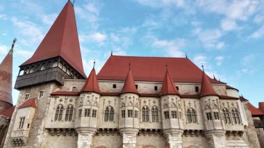 Hunedoara, Transilvanya 'daki Corvin Kalesi' nin insansız hava aracı görüntüsü. Kırmızı kiremitli çatıları, taş kuleleri ve şehrin üzerinde yükselen dramatik savunma duvarları olan Ortaçağ Gotik kalesi.