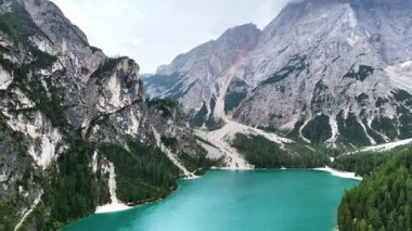 Lago di Braies 'in turkuaz sularının havadan drone görüntüsü yoğun alp ormanı ve İtalya' nın Dolomitler kentindeki dramatik kireçtaşı dağlarıyla çevrili.