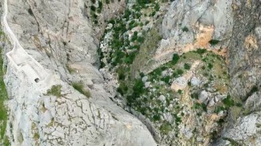 Dağılmış bitki örtüsü ve Mezopotamya 'daki kanyon zemininde akan bir nehrin olduğu derin kayalık bir geçitin hava aracı görüntüsü.