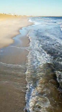 Namibya 'daki uzak İskelet Sahili kıyı şeridinin hava aracı görüntüsü geniş bir kumsal ve çöl kumulları boyunca dalgaların kırıldığını gösteriyor. Dikey