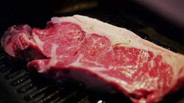 Sıcak ızgarada pişmiş taze çiğ biftek. Görünür baharat ve yağ ile birlikte.