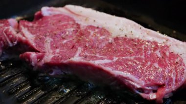 Sıcak ızgarada pişmiş taze çiğ biftek. Görünür baharat ve yağ ile birlikte.