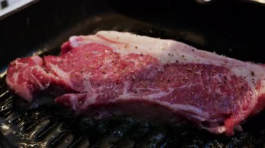 Sıcak ızgarada pişmiş taze çiğ biftek. Görünür baharat ve yağ ile birlikte.