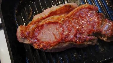 Sıcak ızgarada spatulayla çevirilmiş sulu bir bifteğin kapanışı.