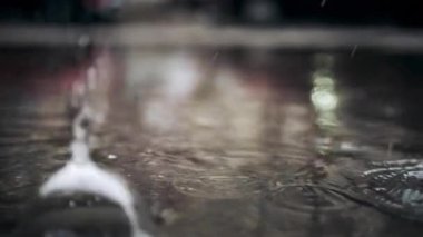 Su damlasını yakın çekim dışarıda ıslak yüzeyde dairesel dalgalanma yaratır.