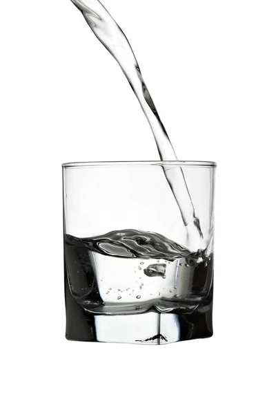Вливание воды в прозрачное стекло, изолированное на белом — стоковое фото
