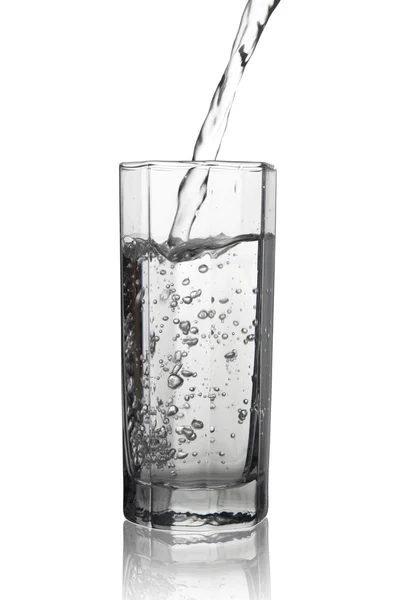 El agua que vierte en un vaso alto con su reflejo, primer plano vie —  Fotos de Stock