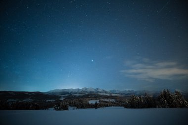 Karlı kış gecesi. Göz kamaştırıcı gece manzarası. Karlı dağların ve vadilerin üzerinde yıldızlarla kaplı bir gökyüzü. Karanlık Noel gecesi.