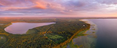 Göllü sonbahar manzarası. Pembe canlı gökyüzünün altında sonbahar manzarası. Göller ve yeşil ormanlarla dolu güzel bir arazide sonbahar gündoğumu. Sahne doğa arkaplanı.