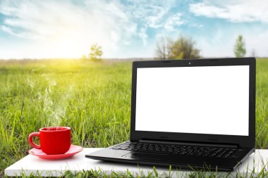 Laptop ve sıcak kahve üzerinde arka plan güzel doğa, açık ofis