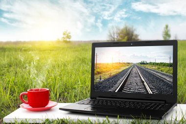 Laptop ve sıcak kahve üzerinde arka plan güzel doğa, açık ofis