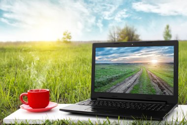 Laptop ve sıcak kahve üzerinde arka plan güzel doğa, açık ofis