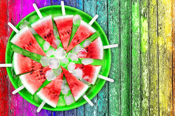 Rebanada de sandía con cubitos de hielo sobre un fondo multicolor —  Fotos de Stock
