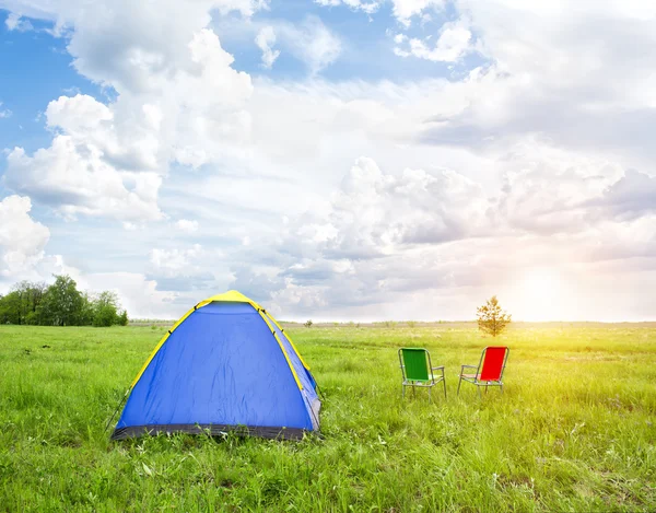 Camping i friska luften vid solnedgången i mitten av gröna ängar — Stockfoto