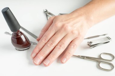 Manikür aletleri ve beyaz arka planda kadın eli. Ev konseptinde manikür yapmak.