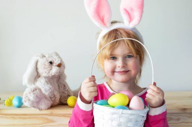 Paskalya tavşanı kulakları takan ve elinde renkli yumurtalarla Paskalya sepeti tutan güzel bir kız. Paskalya bayramı kutlaması ve yumurta avı konsepti.