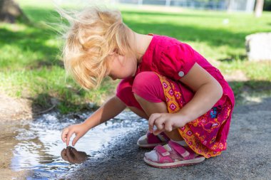 Çocuk yazın parkta kirli su birikintisiyle çıplak ayakla oynuyor. Elektronik aletler olmadan mutlu çocukluk.