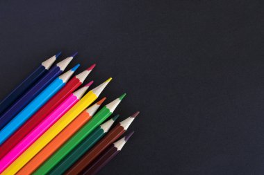 Metin için kopyalama alanı olan siyah arkaplan üzerindeki renkli kalemler.