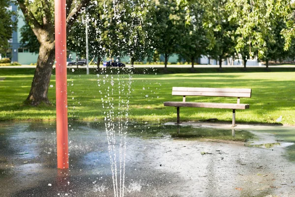 Splash pad in local public park on a summer day with bench