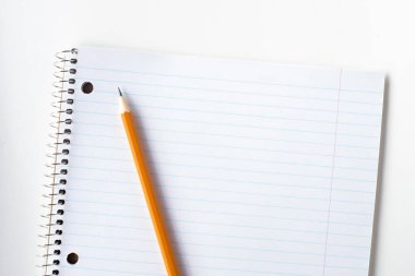 Çizgili boş defter ve kalem. Spiral not defteri ve turuncu kalem..