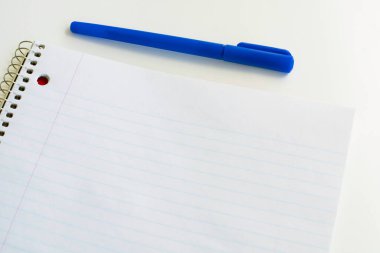 Çizgili boş defter ve kalem. Spiral not defteri ve mavi kalem. Okul malzemeleri.