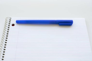 Çizgili boş defter ve kalem. Spiral not defteri ve mavi kalem. Okul malzemeleri.