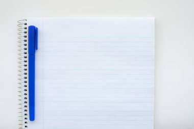 Çizgili boş defter ve kalem. Spiral not defteri ve mavi kalem. Okul malzemeleri.