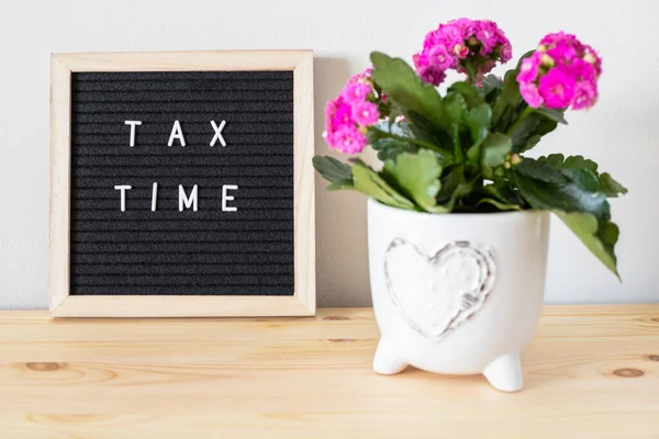 Tax time black felt letter board and flower pots on the table. Business tax return concept.