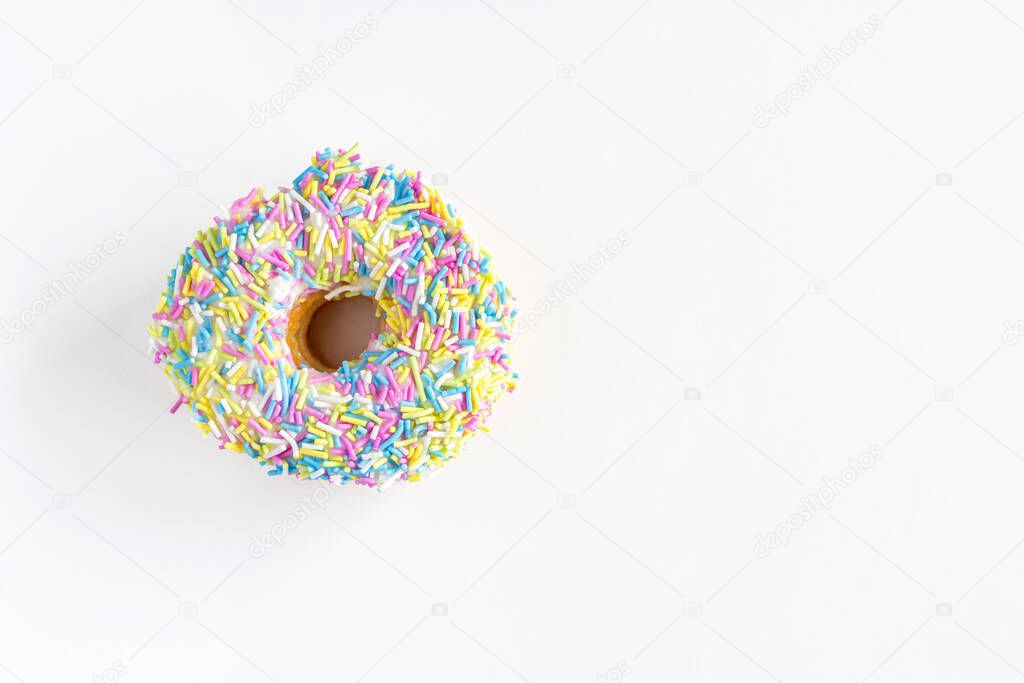 Donut with colorful sprinkles on white background. High angle view with copy space for text.