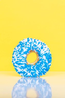 Sarı zemin üzerine mavi ve beyaz serpiştirilmiş çörek, metin için yansıma ve kopyalama alanı.