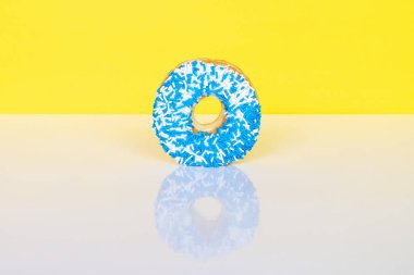 Sarı zemin üzerine mavi ve beyaz serpiştirilmiş çörek, metin için yansıma ve kopyalama alanı.