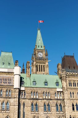 Ottawa, Kanada - 23 Mayıs 2021: Kanada 'nın başkentinde Kanada bayrağı taşıyan parlamento binası, mavi gökyüzüne karşı Ottawa. Yan görünüm.
