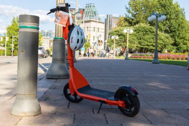Ottawa, Kanada - 2 Ağustos 2021: Sokakta kiralık kasklı elektrikli scooter. Şehir merkezinde kaldırıma park etmiş turuncu bir e-scooter.