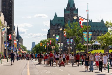 Kanada, Ottawa - 1 Temmuz 2024: Kanada Ulusal Başkent Günü. Parlamento Tepesi yakınlarındaki Wellington caddesinde kırmızı beyaz giysiler içinde yürüyen insanlar..