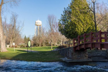 Perth, Kanada -27 Nisan 2025: Stewart Park Perth, Ontario, Kanada ilkbaharda. Nehir üzerinde kırmızı ahşap köprü
