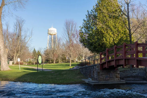 Perth, Kanada -27 Nisan 2025: Stewart Park Perth, Ontario, Kanada ilkbaharda. Nehir üzerinde kırmızı ahşap köprü