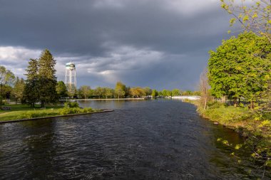 Smiths Falls, Kanada - 25 Mayıs 2025: Rideau Nehri küçük Ontario kasabasında ve ilkbaharda su kulesinde. Dramatik fırtınalı gökyüzü