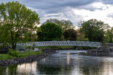 Rideau Nehri 'ni geçen uzun beyaz metal köprü. Ontario parkı manzaralı kemerli yaya köprüsü..